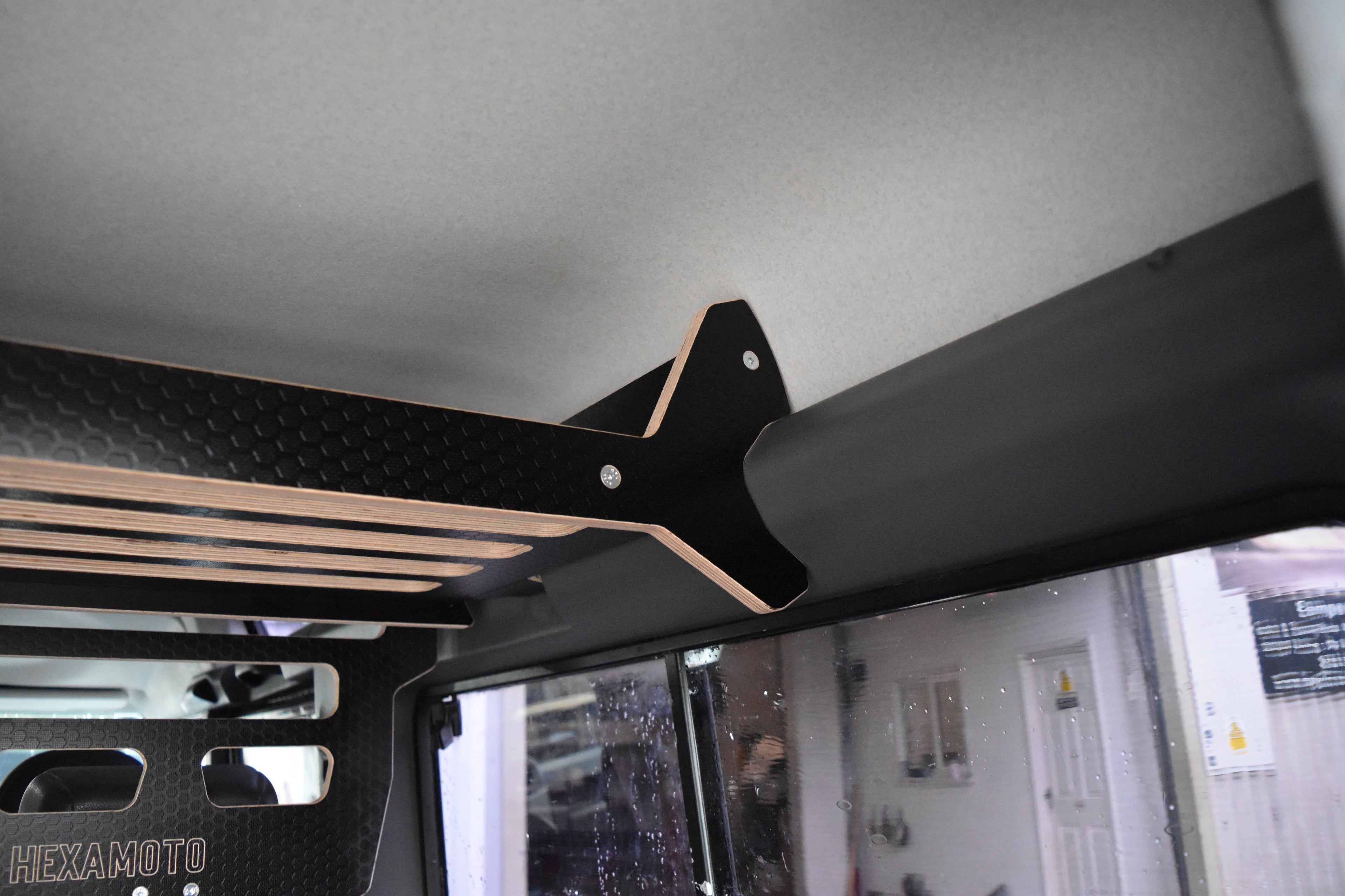 Ceiling mount bracket on a vehicle interior with visible brand 'Hexamoto'.