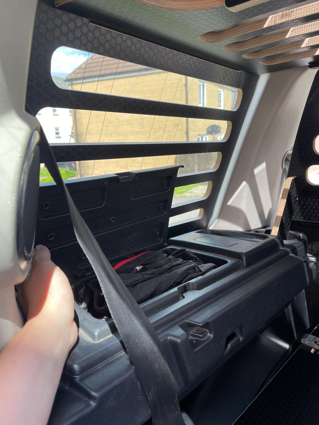 Person showing that the side storage compartments in a car can still be used with a storage system