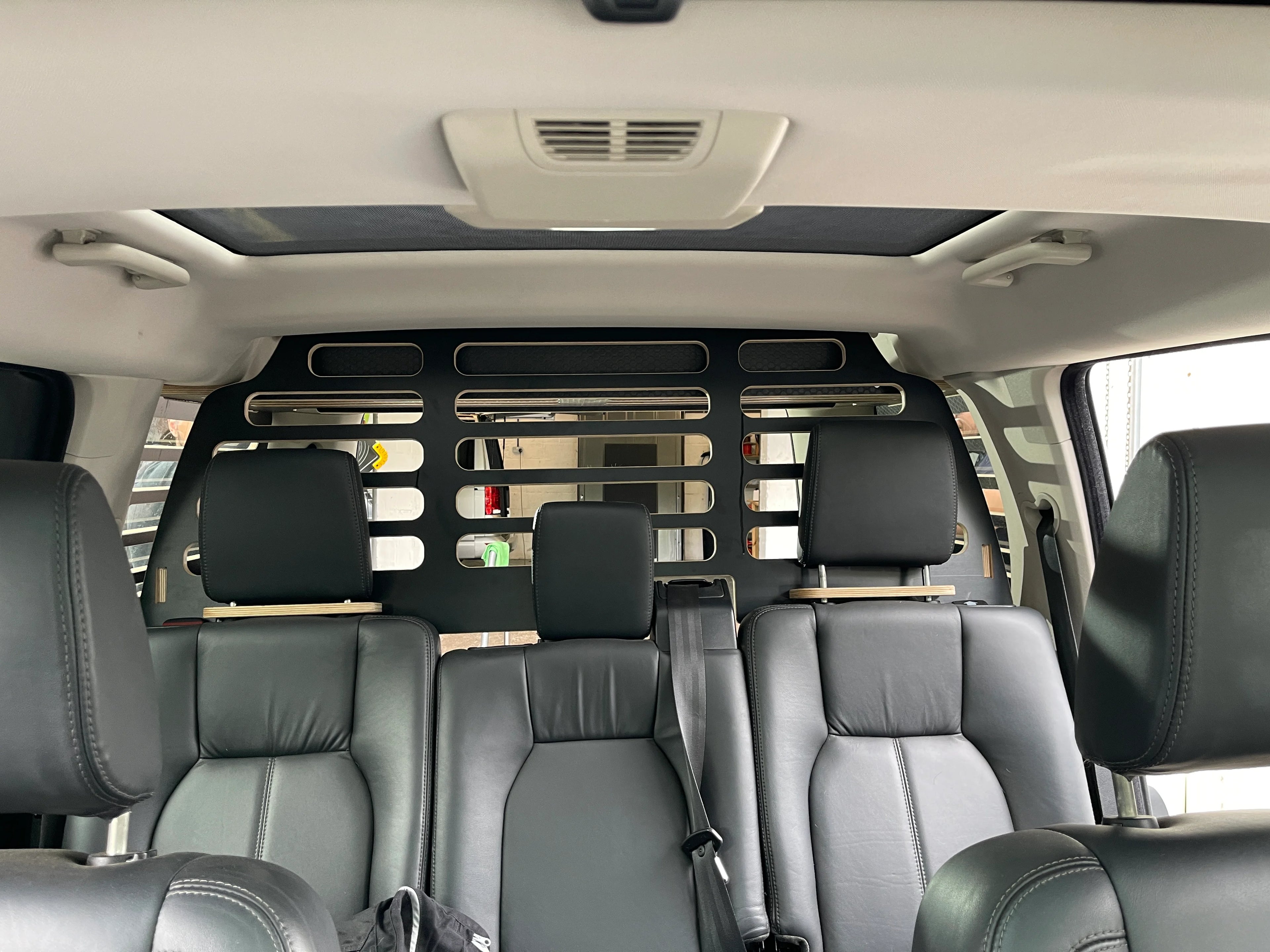 Interior of a vehicle with black leather seats and a partition Dog Guard